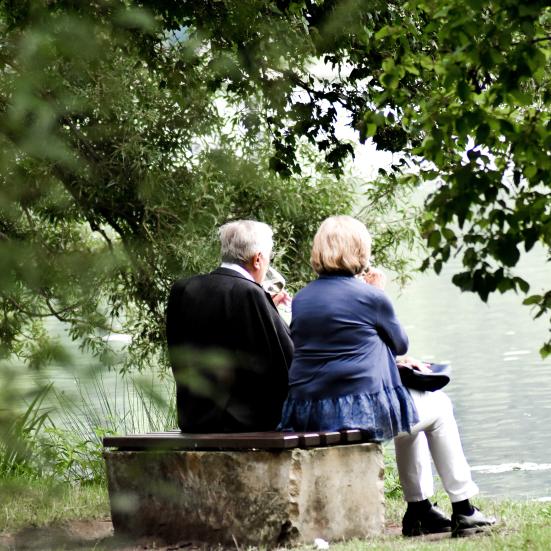 To mennesker der sidder på en bænk og kigger ud over en sø
