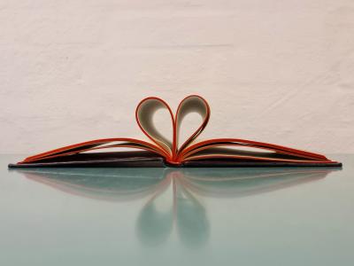 Åben bog med sider foldet som et hjerte, der illustrerer læseglæde