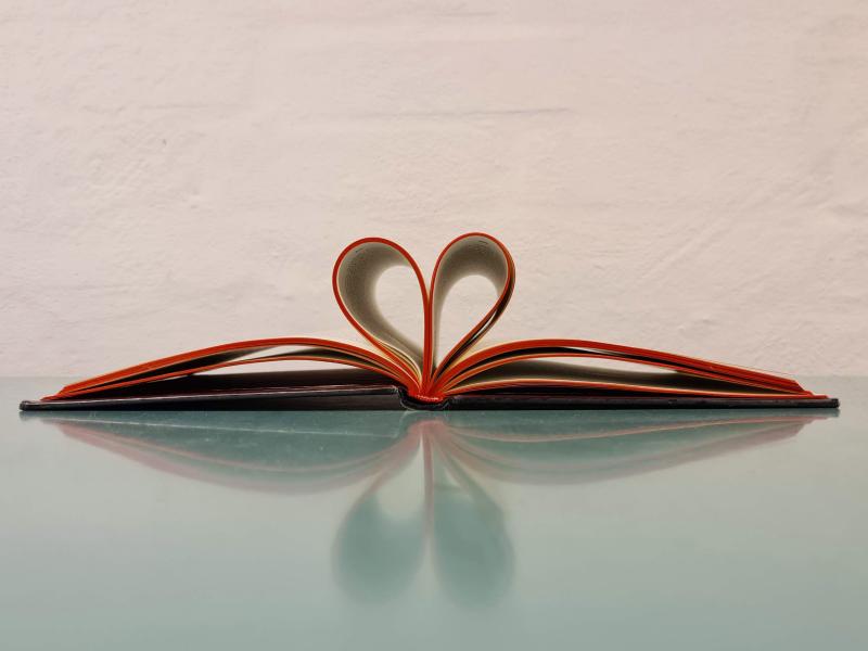 Åben bog med sider foldet som et hjerte, der illustrerer læseglæde