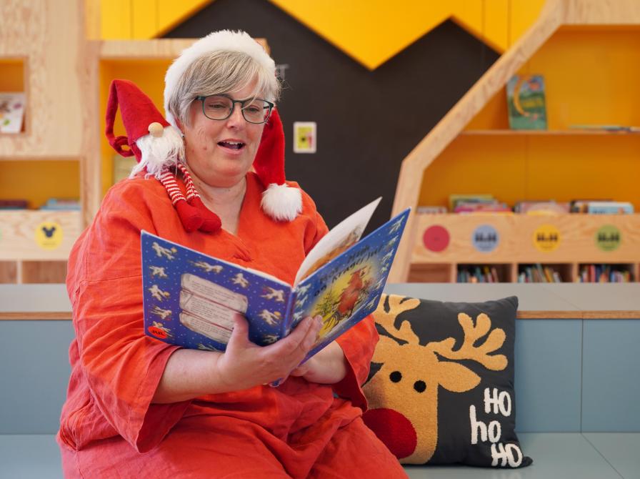 Dame i juletøj sidder og læser højt