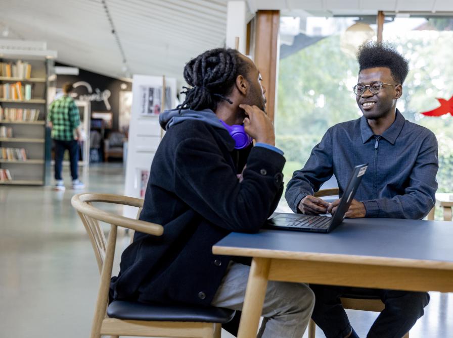 To unge mænd i samtale ved et bord