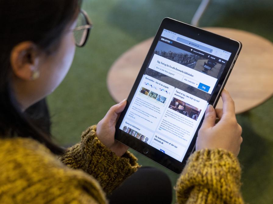 Ung kvinde der læser på en ipad