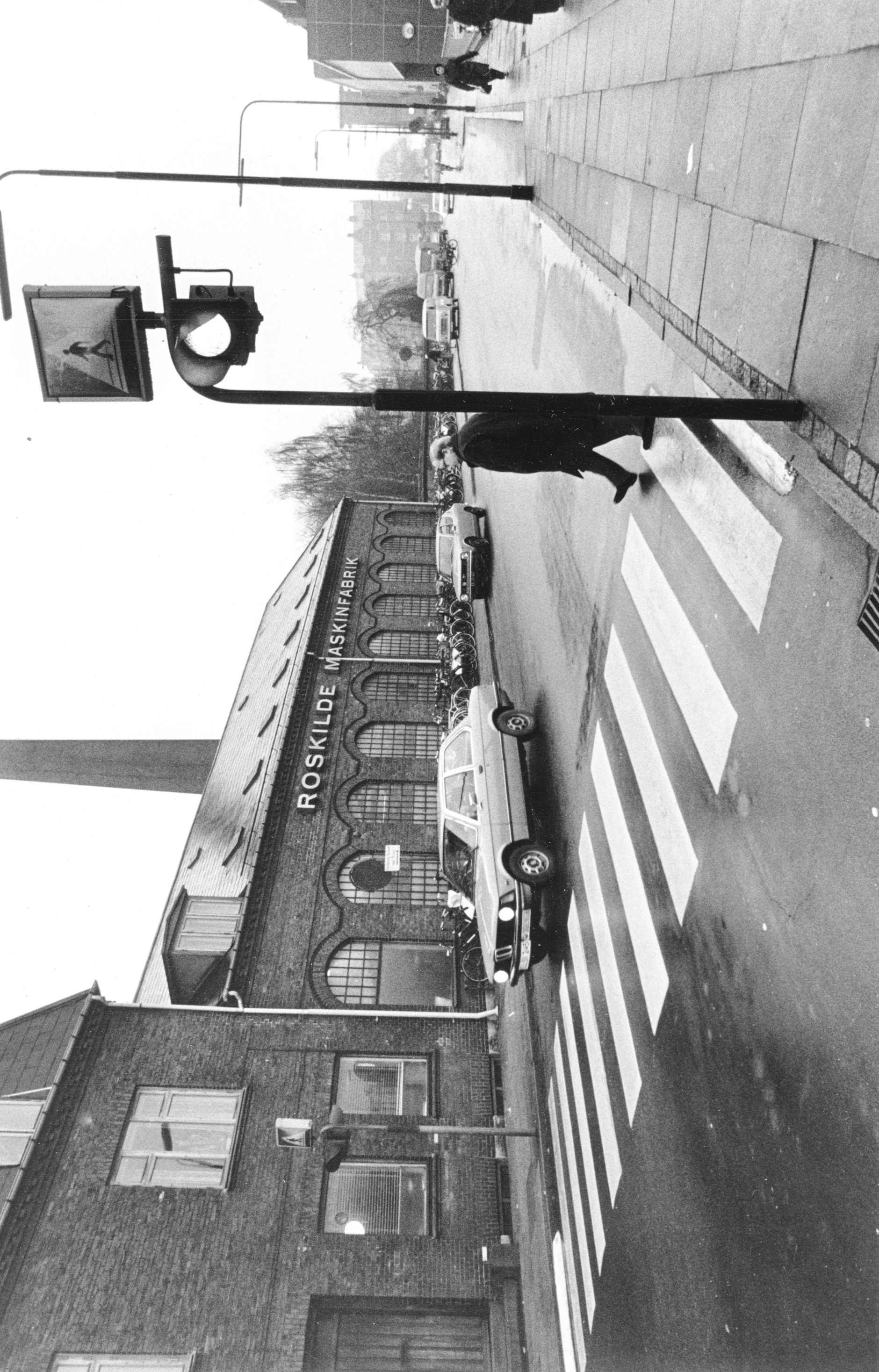 Sort/hvid-foto af fodgængerfelt ved Roskilde Maskinfabrik med fodgænger og bil.
