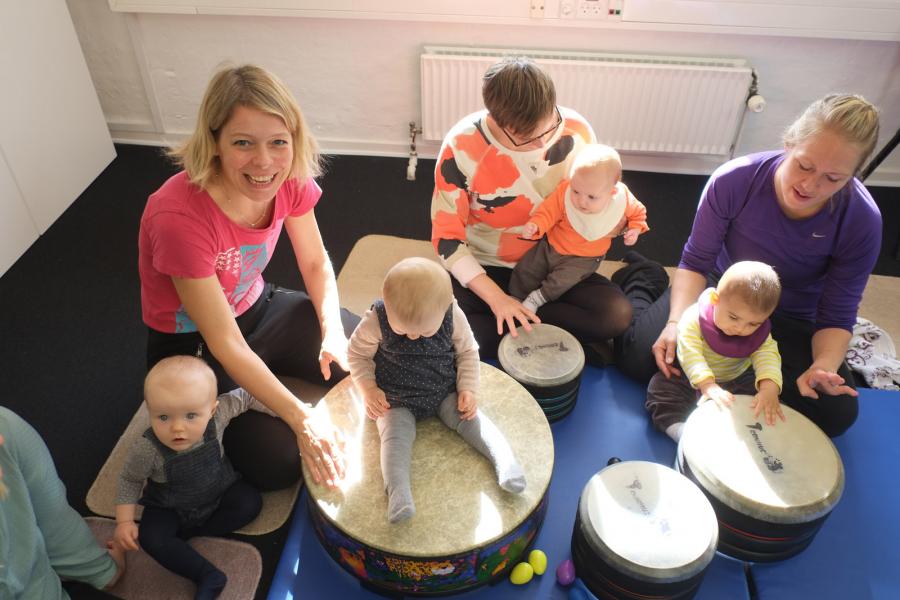 Musiklærer sidder med en masse babyer og trommer